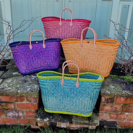 Four colorful woven baskets on a stone ledge with a light blue wall in the background.