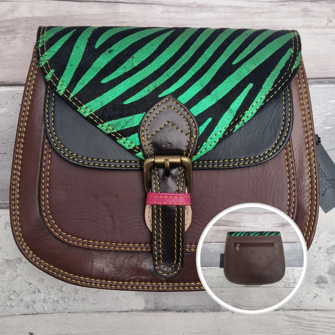 Saddlebag style bag in brown coloured leather with contrasting coloured panels and a section of textured metallic green zebra print.
