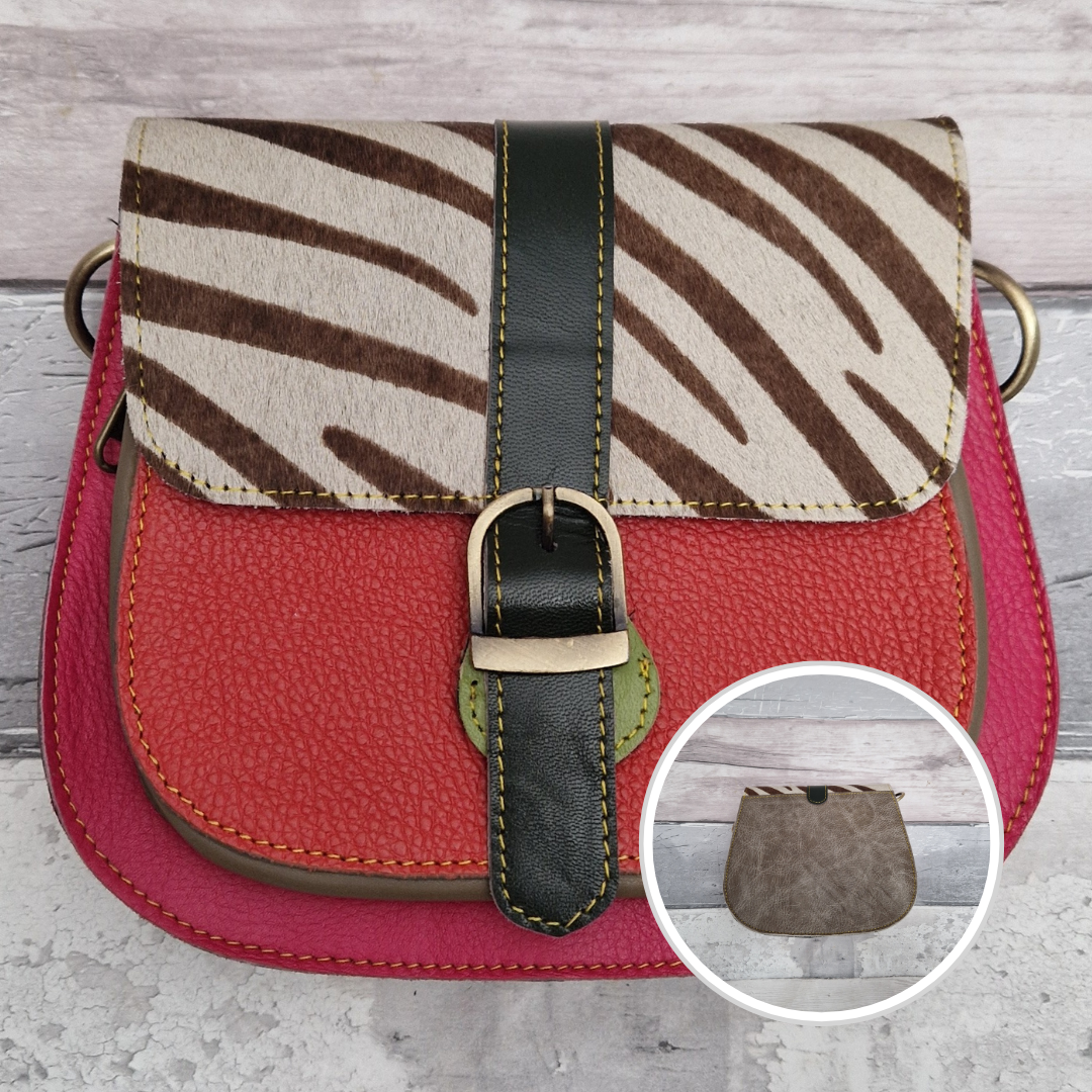 All leather saddlebag style ladies bag in 2 tones of red and pink with a textured panel of zebra print. Brass buckle closer.