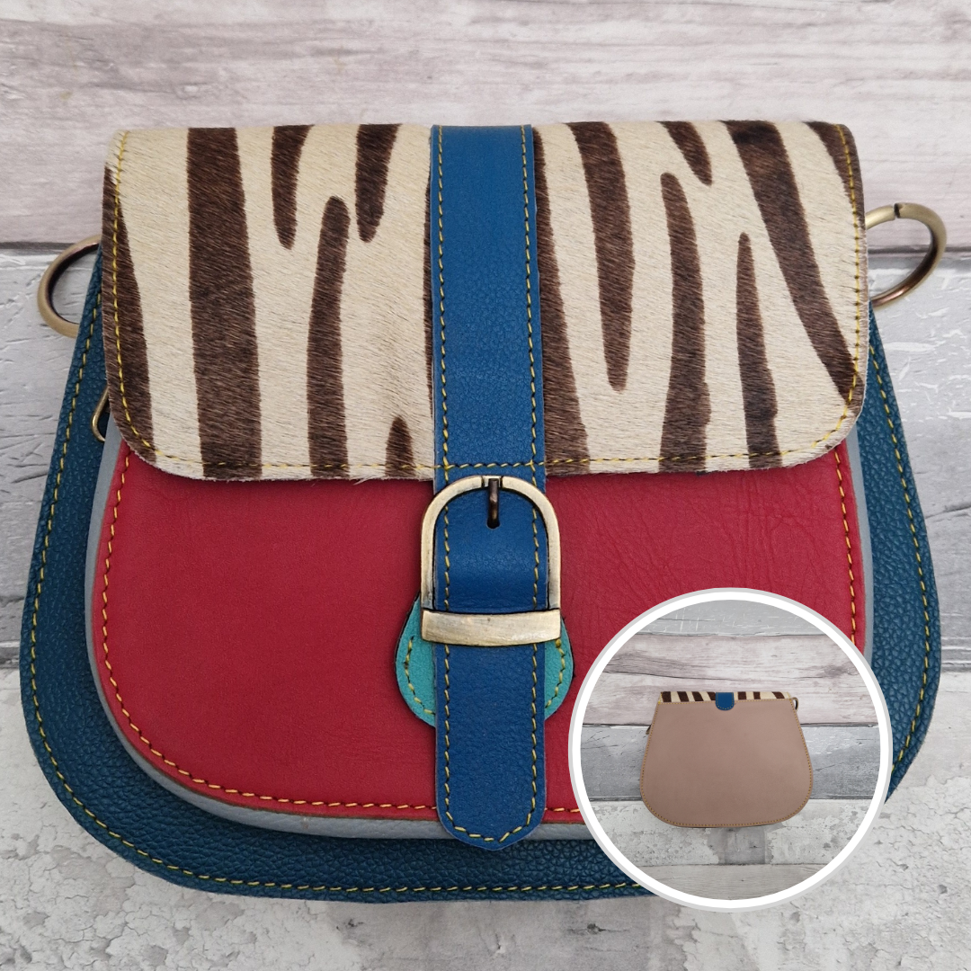 All leather saddlebag style ladies bag in 2 tones of blue and red with a textured panel of zebra print. Brass buckle closer.