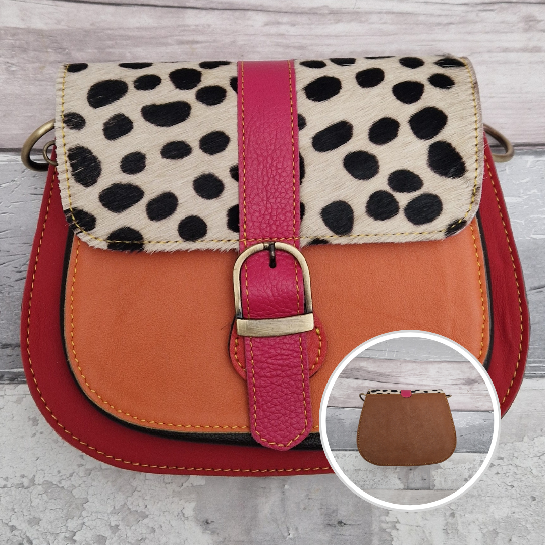 All leather saddlebag style ladies bag in 2 tones of red, peach and pink with a textured panel of spot print. Brass buckle closer.