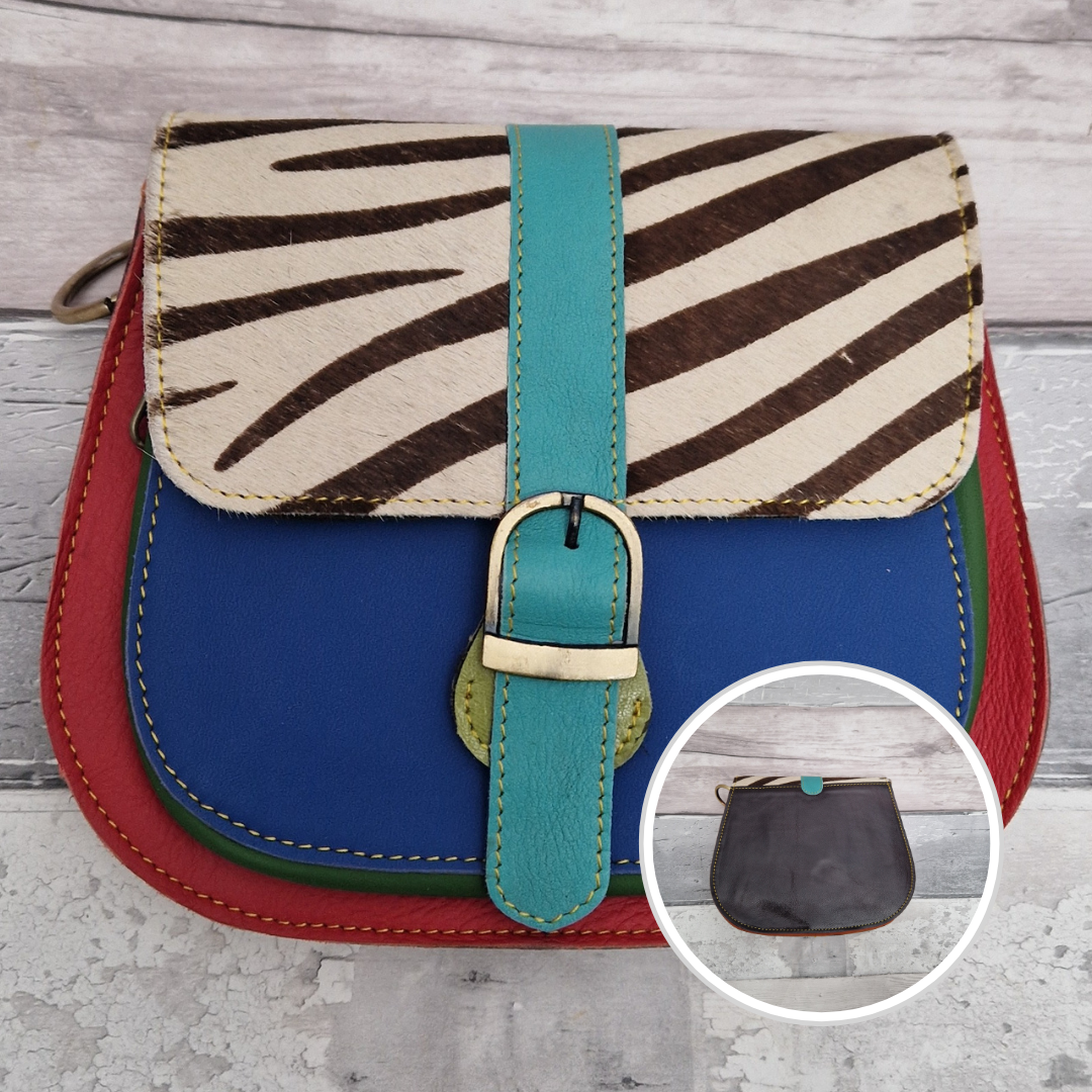 All leather saddlebag style ladies bag in 2 tones of blue and red with a textured panel of zebra print. Brass buckle closer.