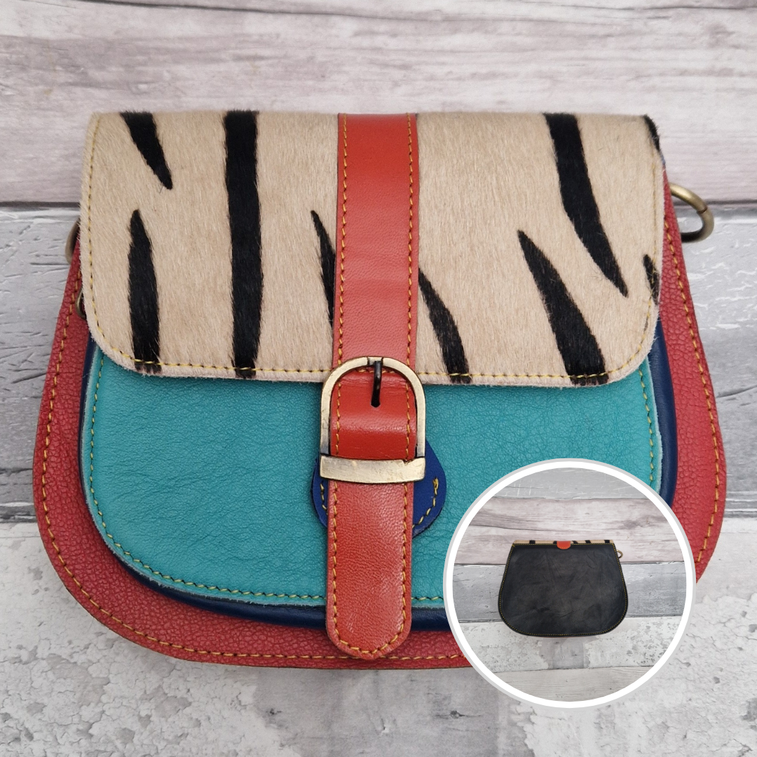 All leather saddlebag style ladies bag in 2 tones of red and blue with a textured panel of zebra print. Brass buckle closer.