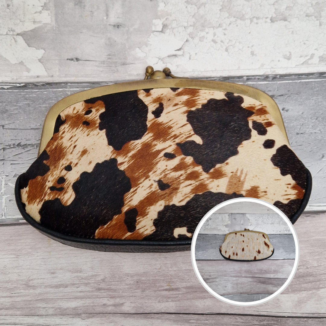 Cow print clutch bag on a wooden surface.