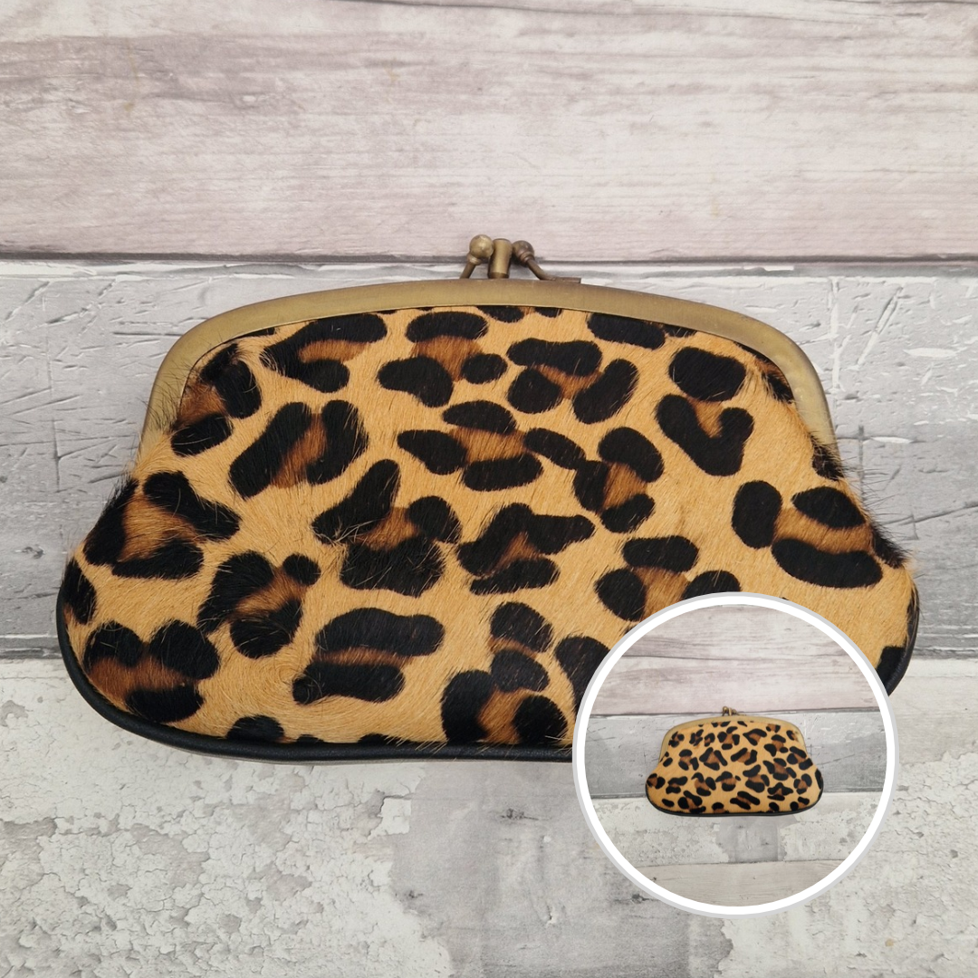 A leopard print faux fur kiss-lock clutch bag with a brass metal frame, shown on a light gray wood-textured background with a circular inset showing the front view.