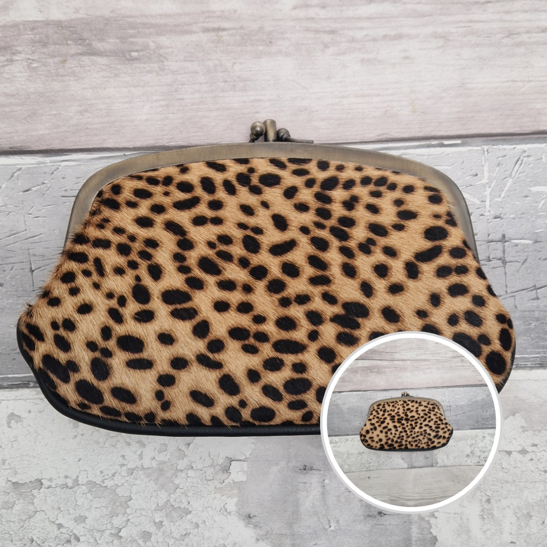 Cheetah print kiss-lock clutch purse with a gold-tone metal frame, shown on a distressed gray wood background with a circular inset showing the front view.