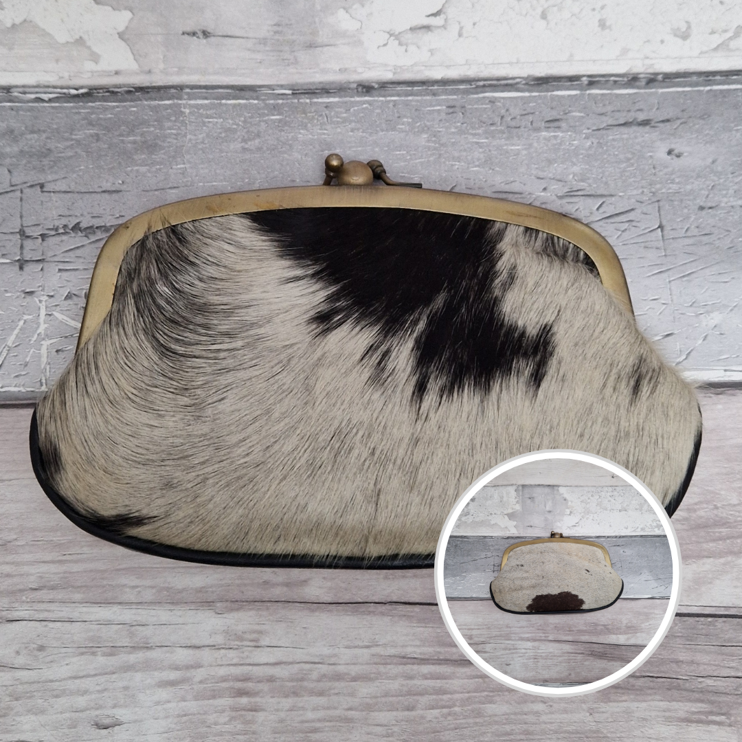 Clutch bag with cowhide pattern on a wooden surface