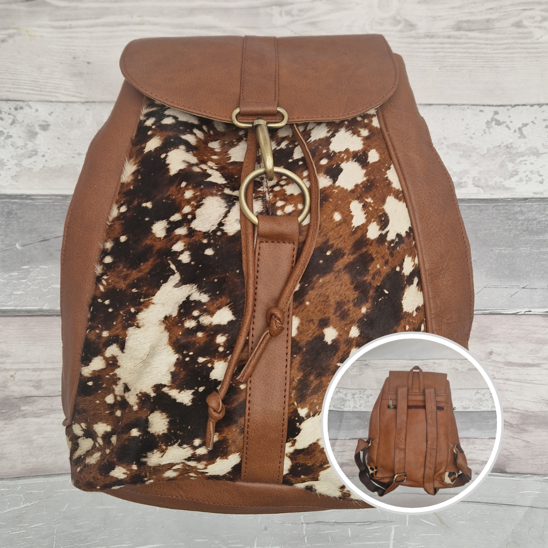 Brown leather backpack with cowhide pattern on a wooden surface