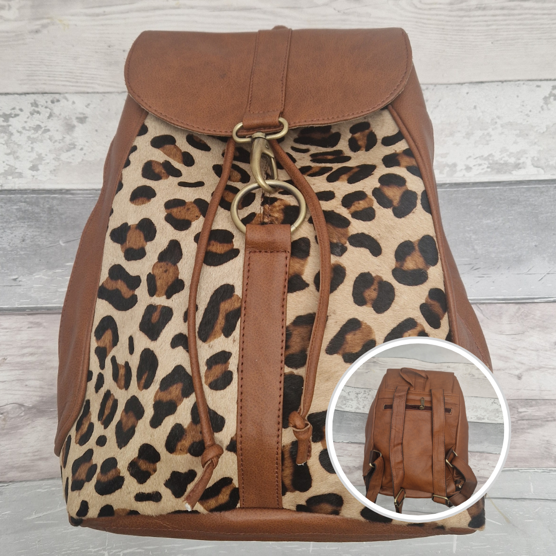 Leopard print backpack with brown leather accents on a wooden surface