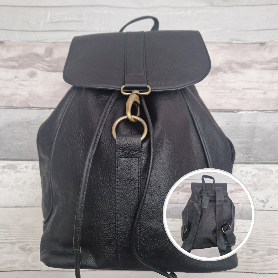 Black leather backpack with gold buckle on a wooden surface