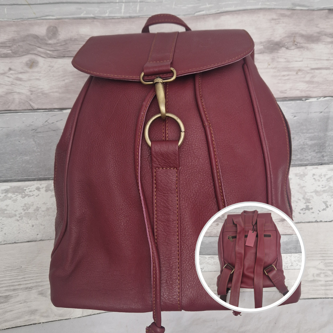 Maroon backpack with gold buckle on a wooden surface