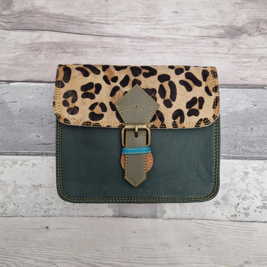 Square pill box shaped all leather bag with a green front and textured panel of leopard animal print.
