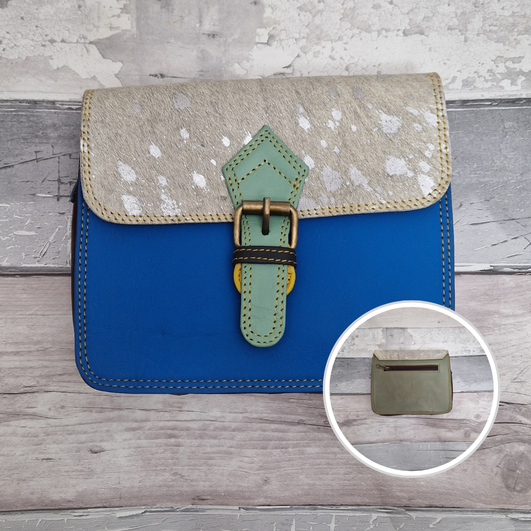 Square pill box shaped all leather bag with a blue front and textured panel of metallic cow print.