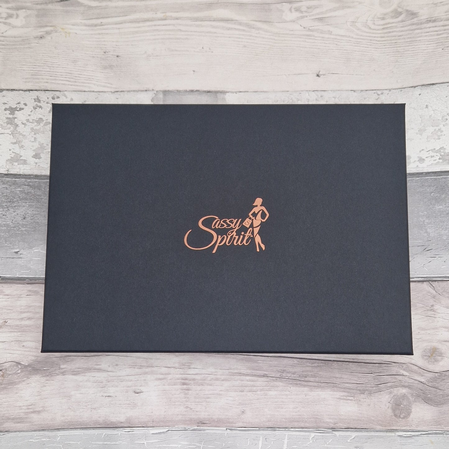 Black box with 'Sassy Spirit' logo on a wooden surface