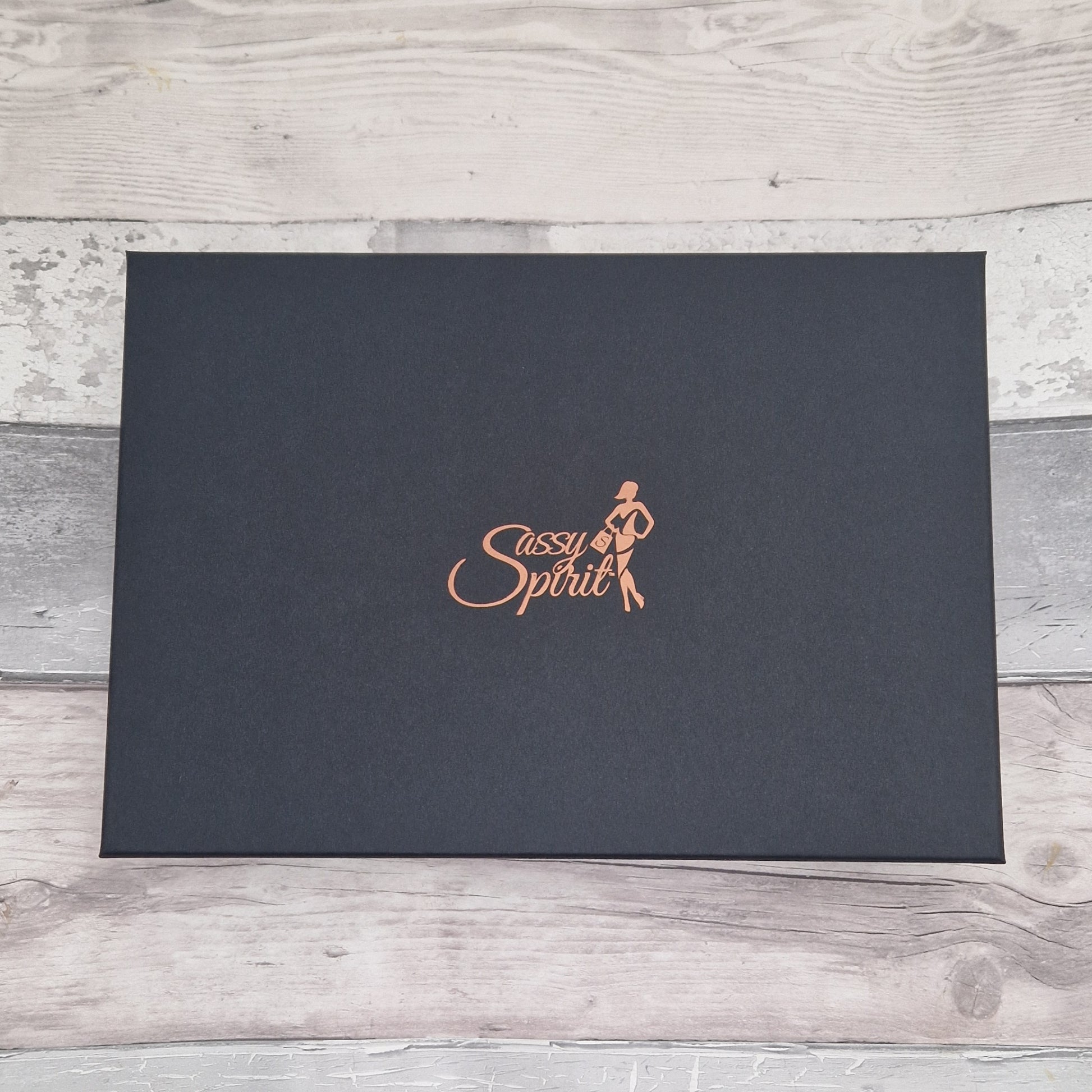 Black box with 'Sassy Spirit' logo on a wooden surface