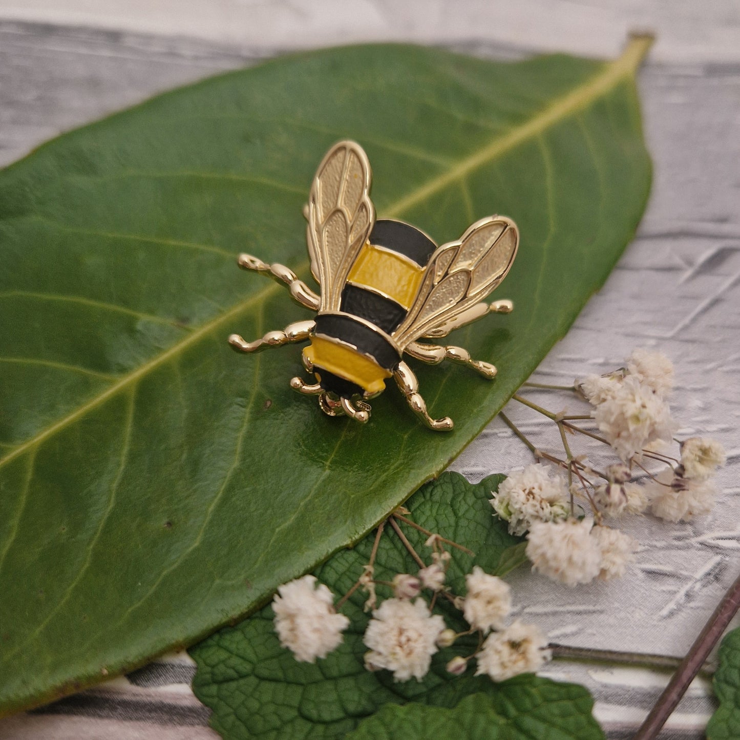 Photo of a life like Bumble Bee Brooch in vivid yellow and black stripes with gold wings and legs