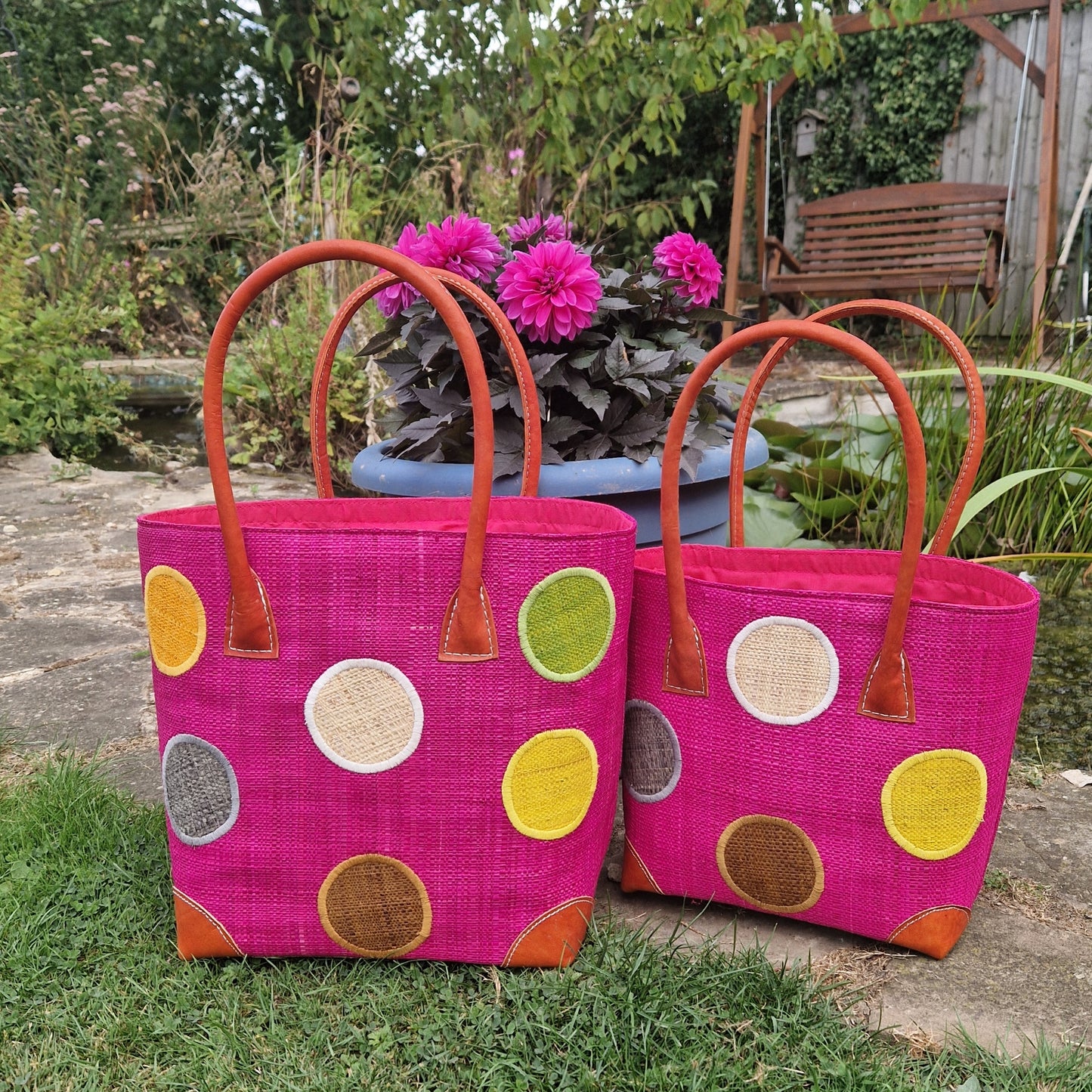 Pink Raffia baskets with leather handles decorated with multi coloured spots.