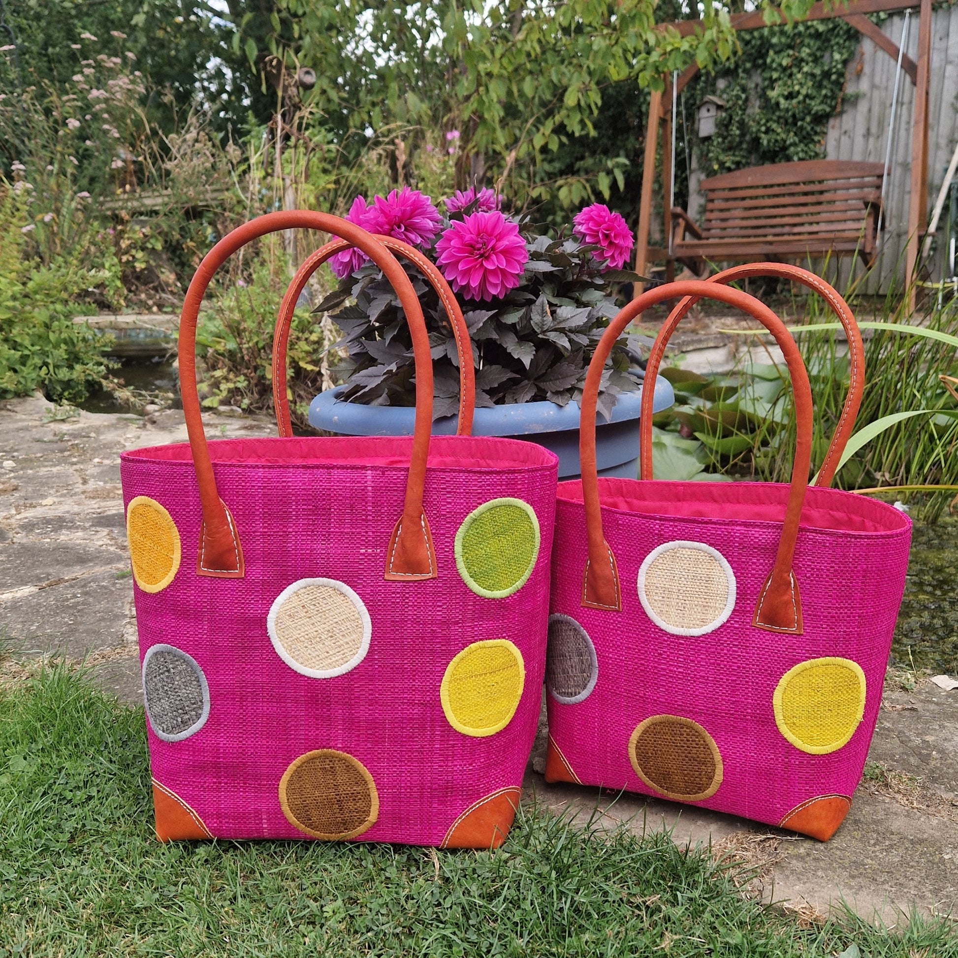 Pink Raffia baskets with leather handles decorated with multi coloured spots.