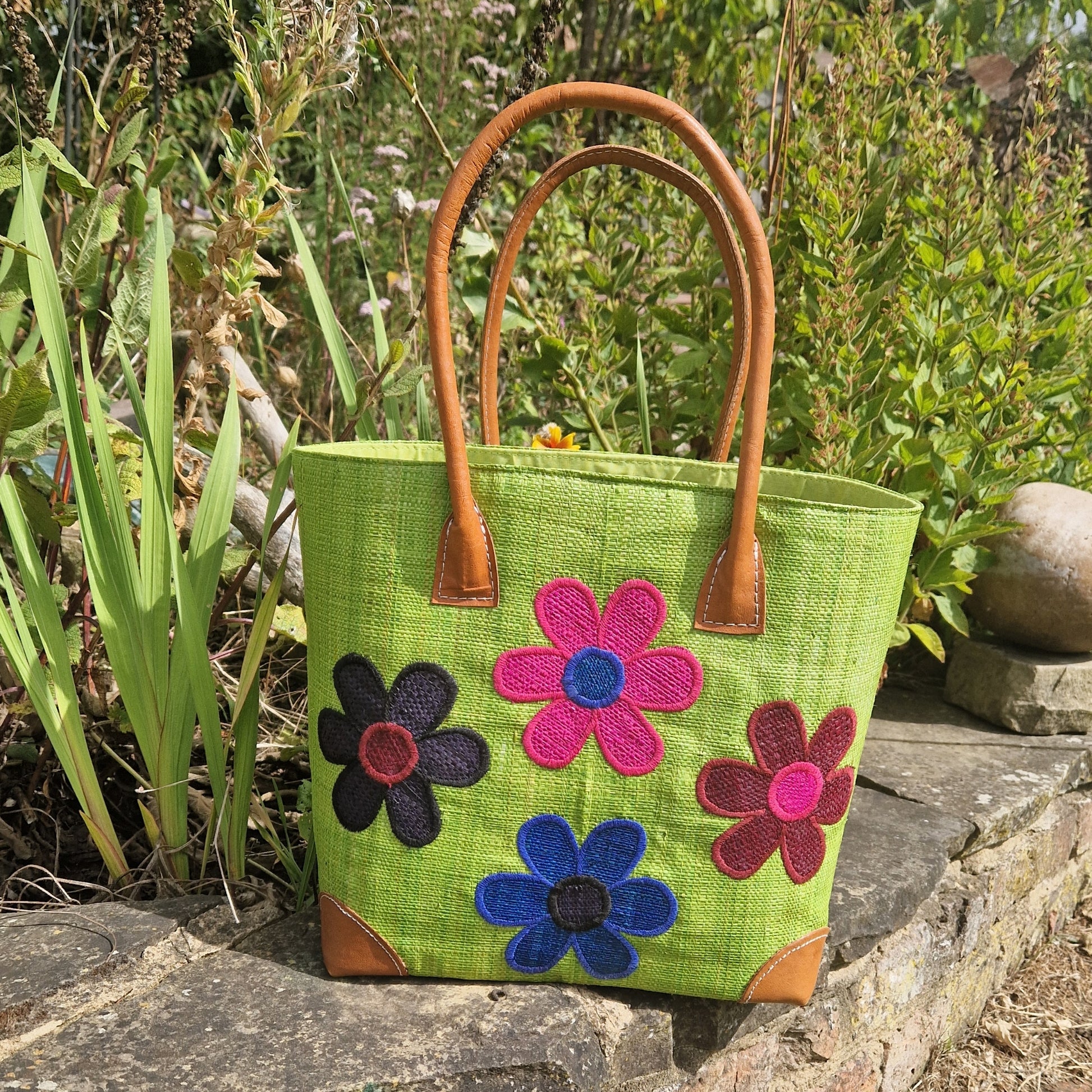 Lime Green Raffia basket with leather handles decorated with 4 brightly coloured flowers.