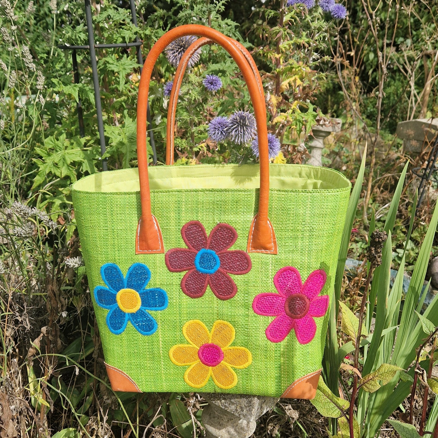 Lime Green Raffia basket with leather handles decorated with 4 brightly coloured flowers.