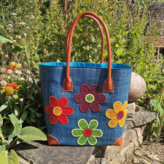 Teal Blue Raffia Basket with leather handles. Front panel decorated with 4 multi-coloured flowers.