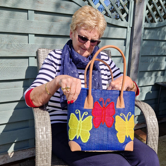 Lady sat looking into a Royal Blue Basket decorated with multi-coloured butterflies.