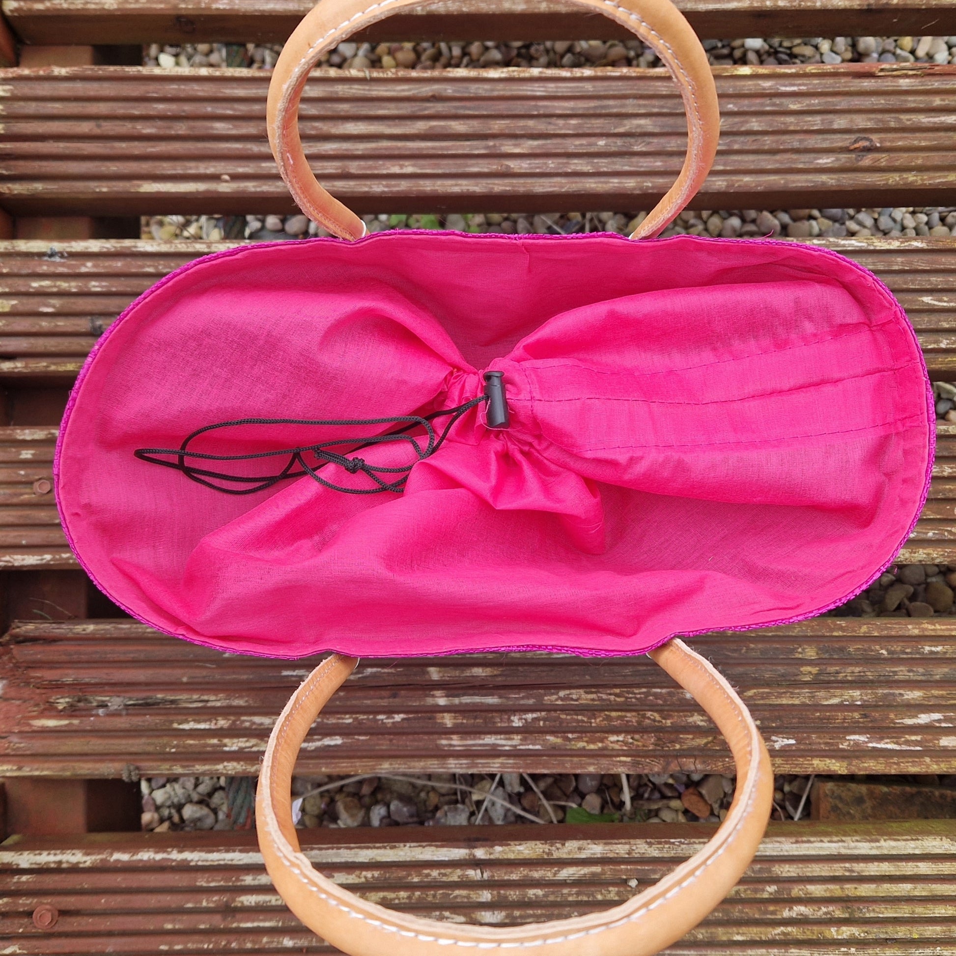 Top down view of pink raffia basket with drawstring top.
