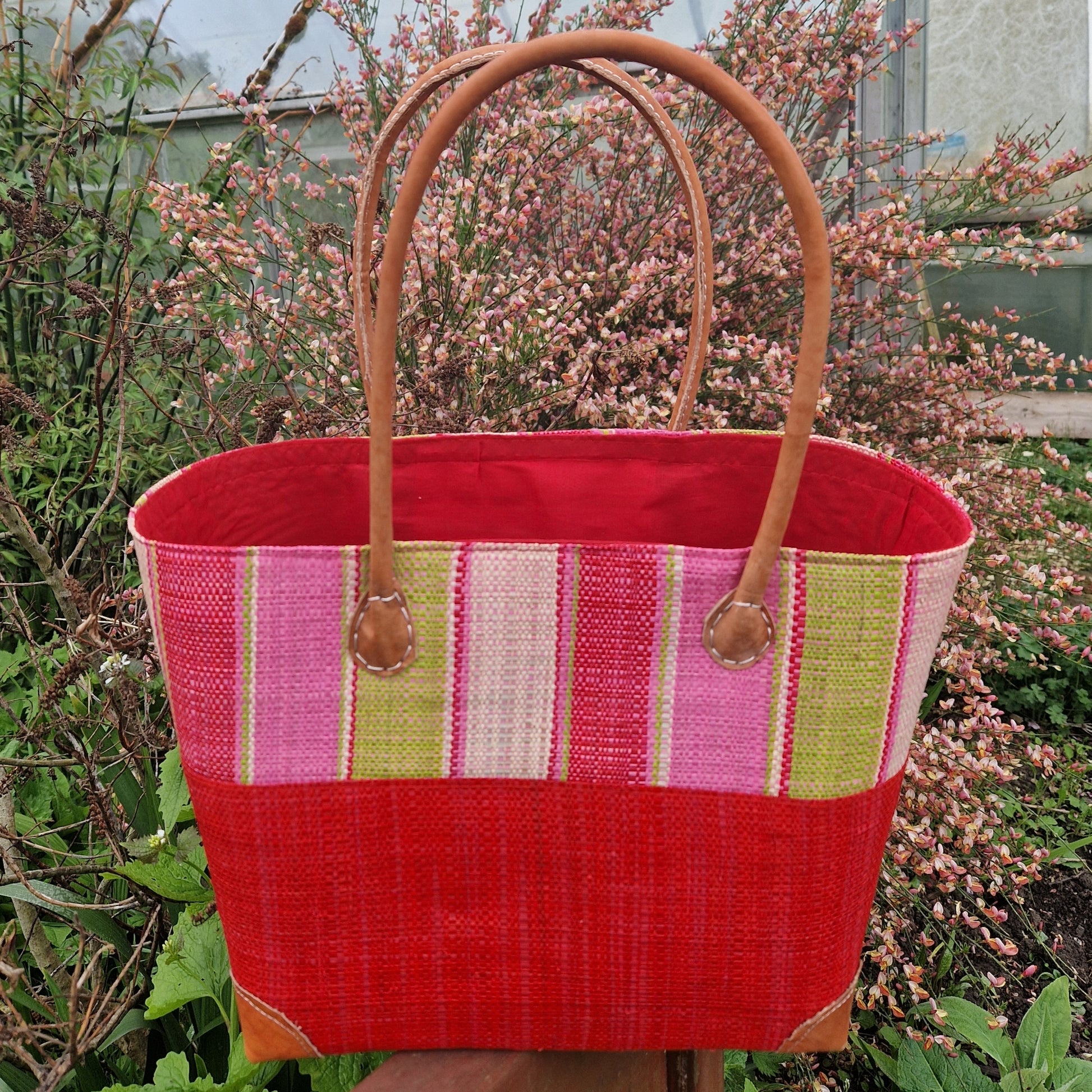 Red raffia basket with coloured stripes.