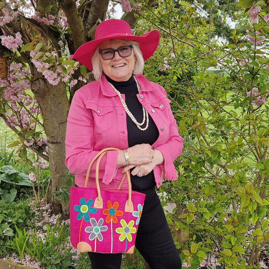 Lady wearing a pink hat and carrying a pink basket with flowers on it.