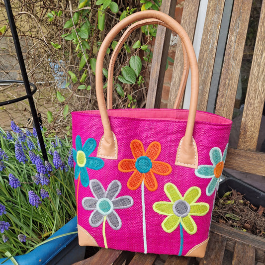 Hot Pink coloured Raffia Basket with brightly coloured flowers on the front.