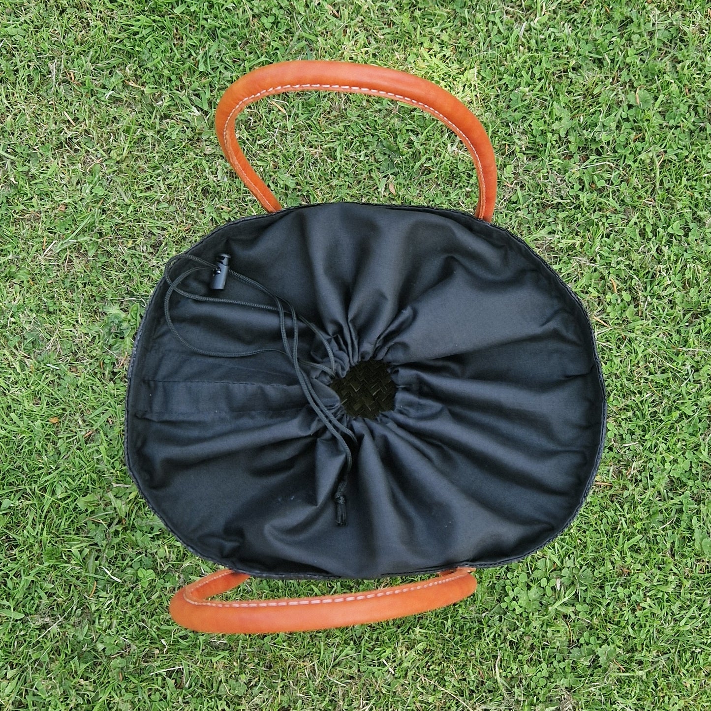 Top down view of drawstring top on black raffia basket.