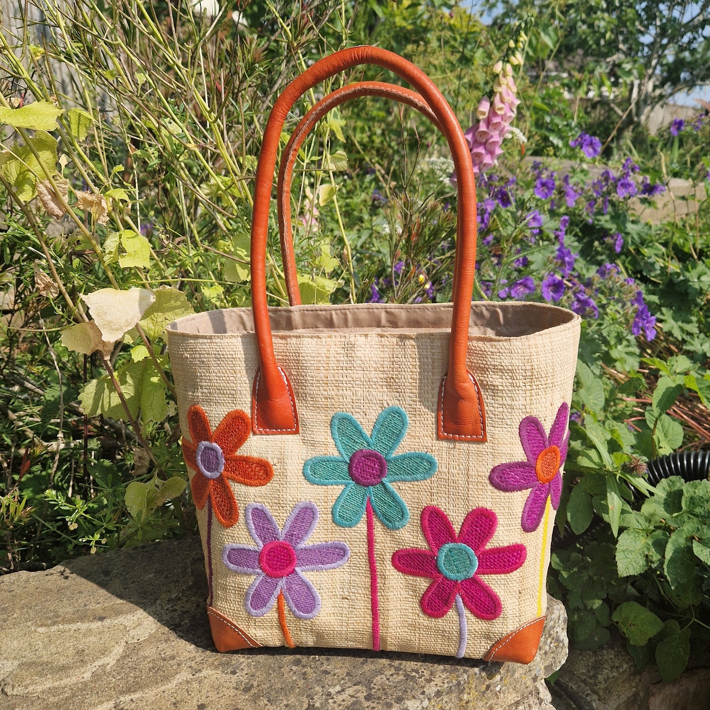 Natural Raffia basket with leather handles. Decorated with an image of 5 multi-coloured flower stems.