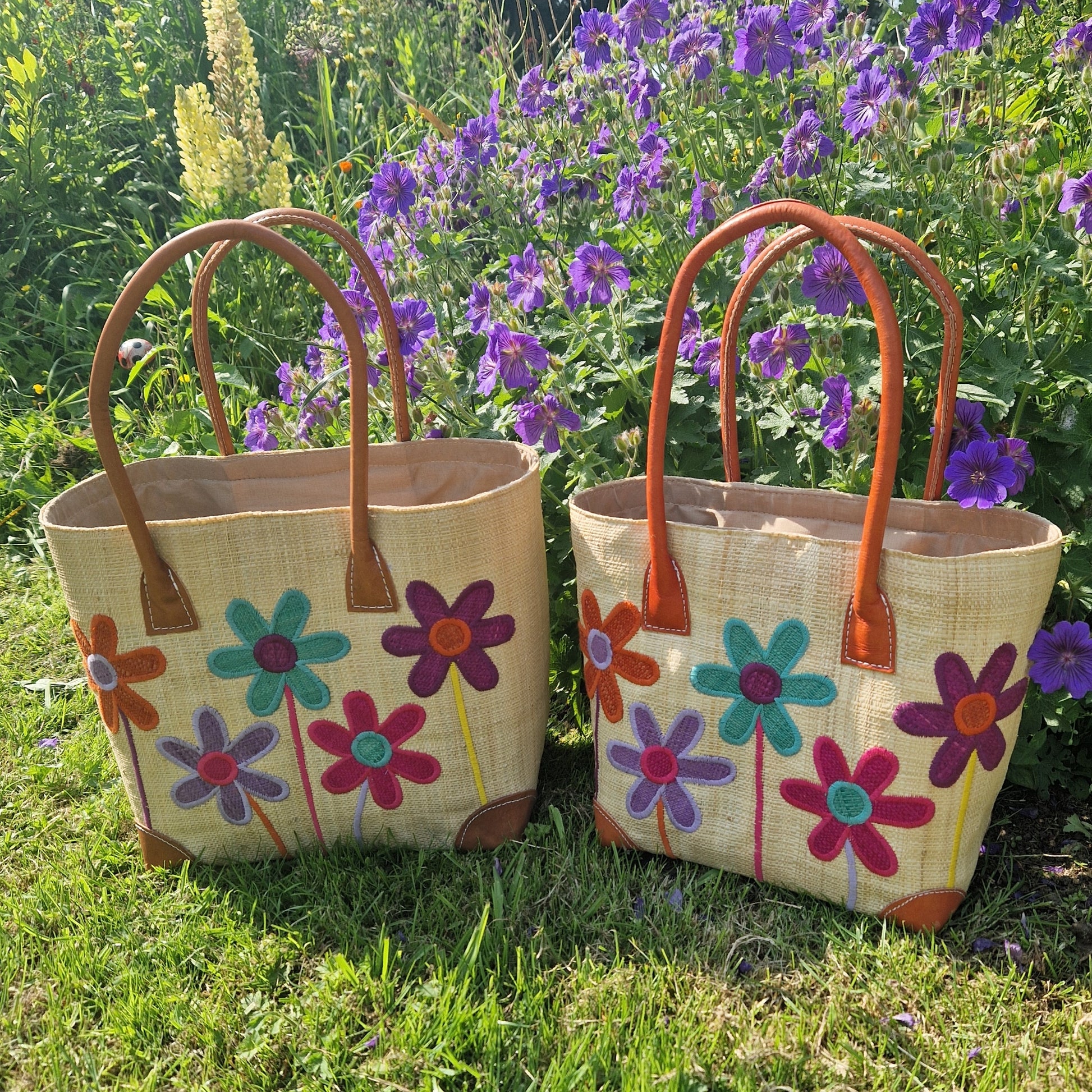 Natural Raffia baskets with leather handles. Decorated with an image of 5 multi-coloured flower stems.