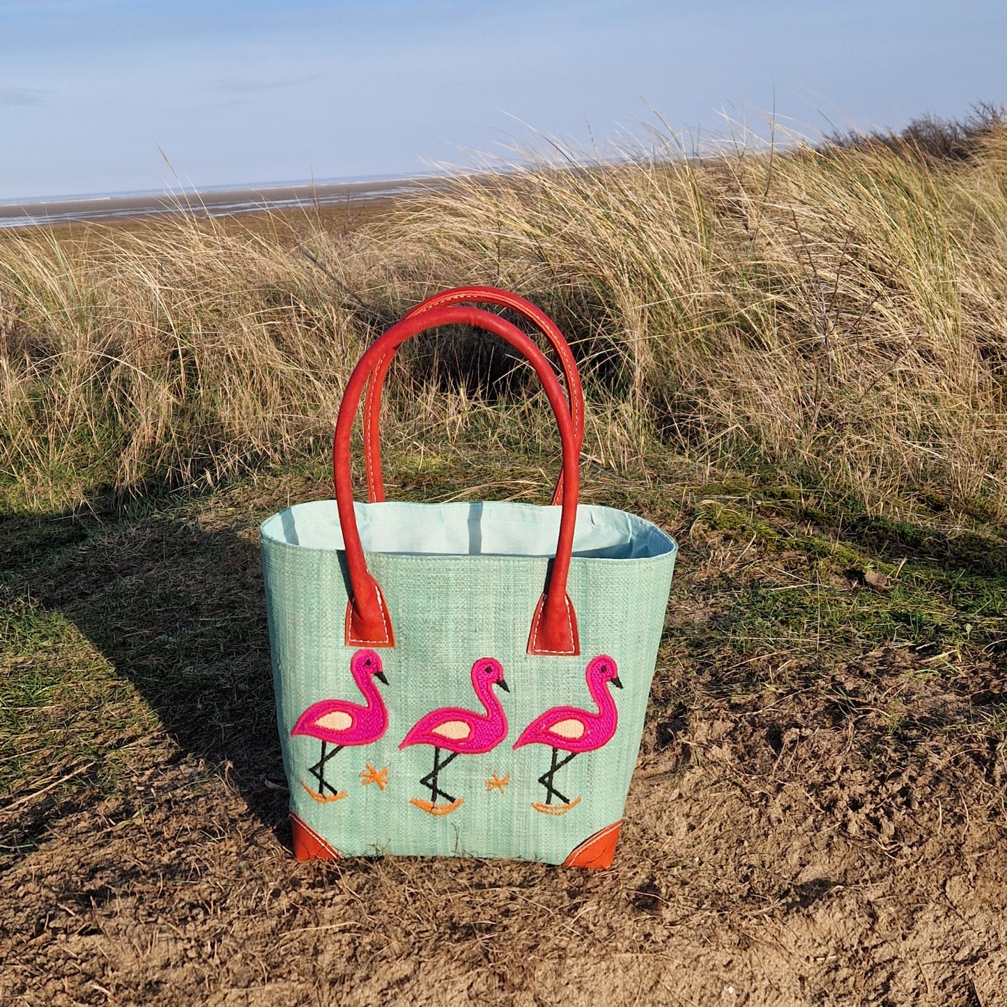 Mint coloured raffia basket decorated with pink flamingos.