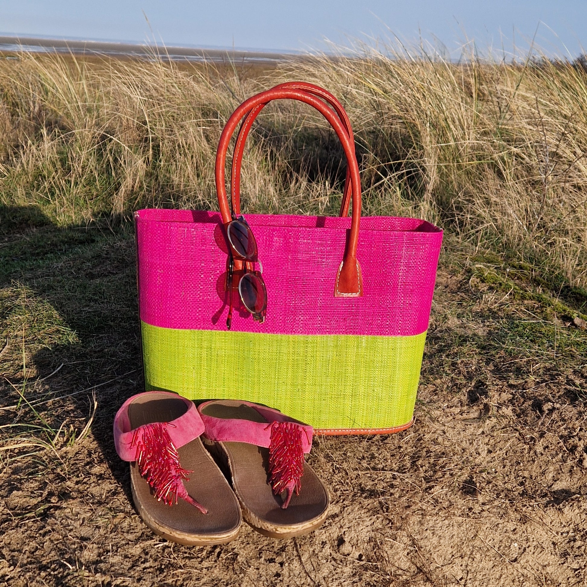 Raffia basket with leather handles in panels of hot pink and lime.