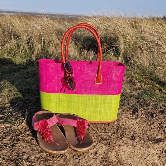 Raffia basket with leather handles in panels of hot pink and lime.