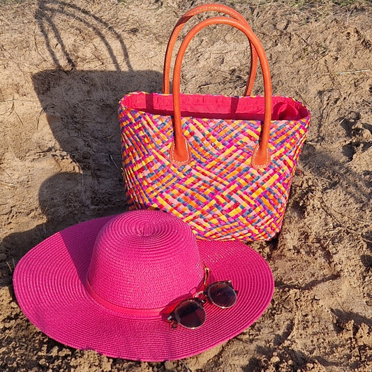 Raffia basket with a multicoloured patchwork pattern and matching pink wide brimmed hat.