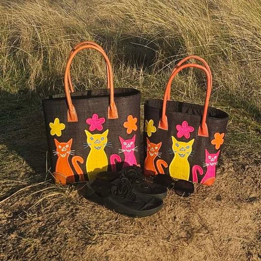 2 Black Raffia Baskets decorated with colourful cheeky cats in bright pink, yellow and orange.