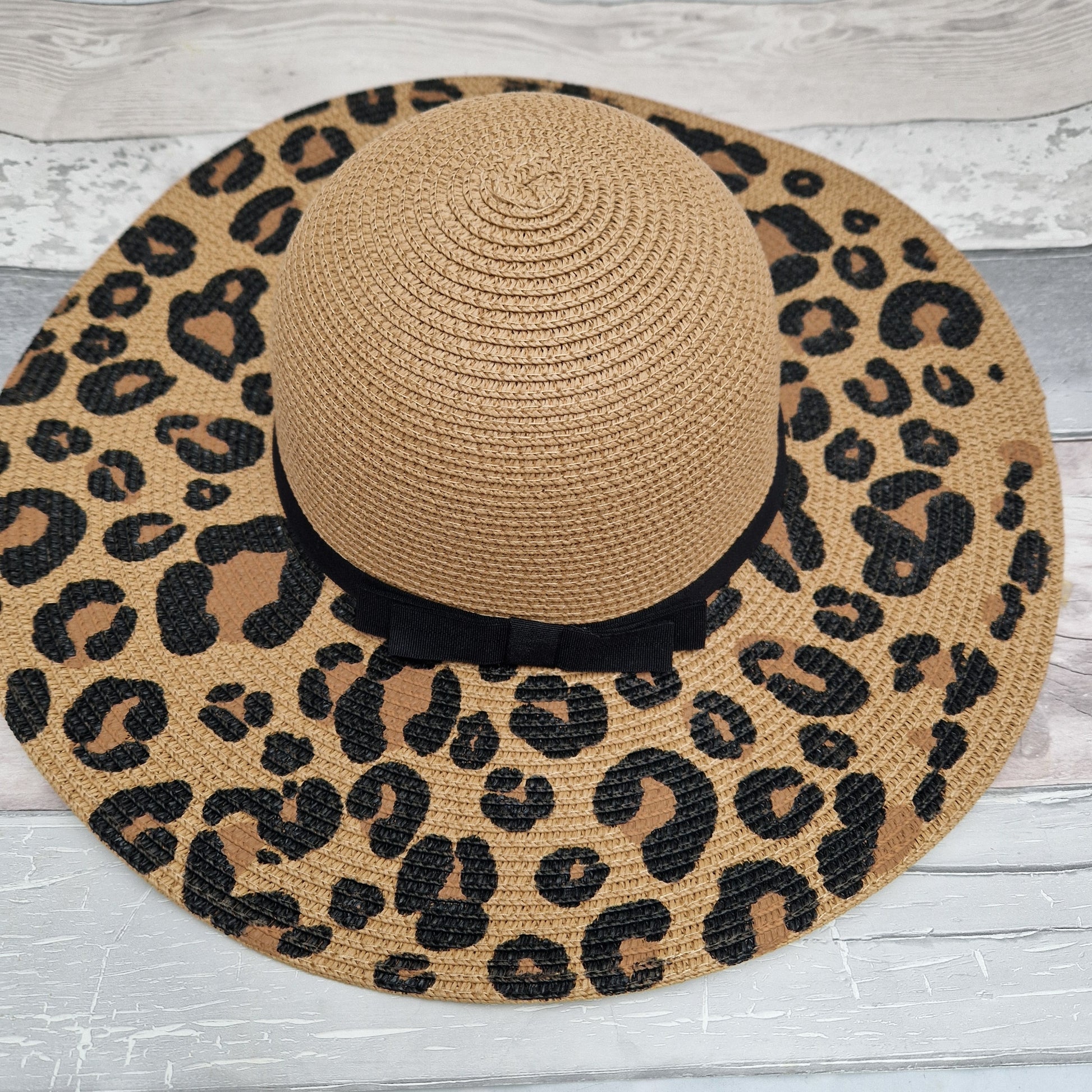 Wide brimmed biscuit coloured hat with leopard print across the brim and a black ribbon band.