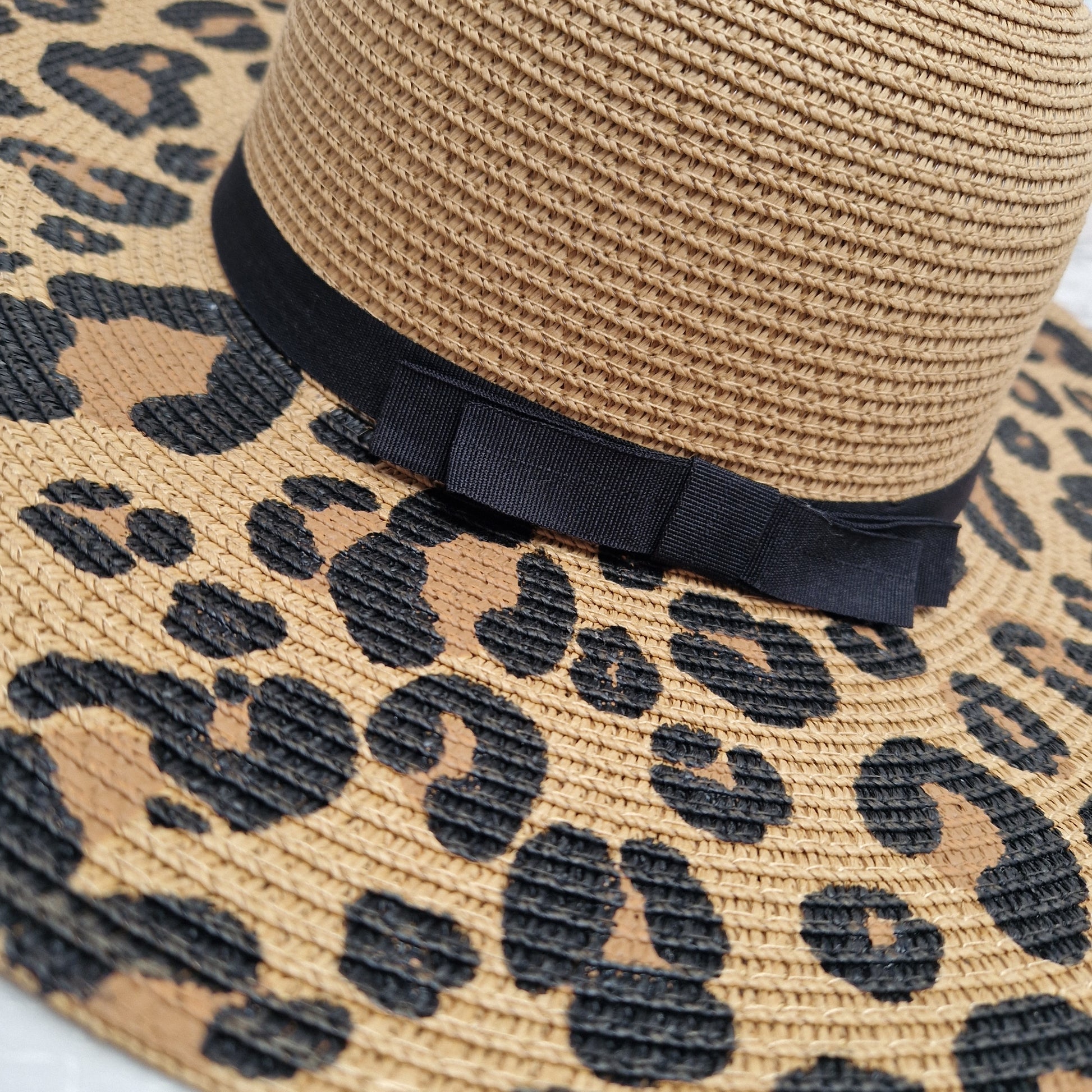 Wide brimmed biscuit coloured hat with leopard print across the brim and a black ribbon band.