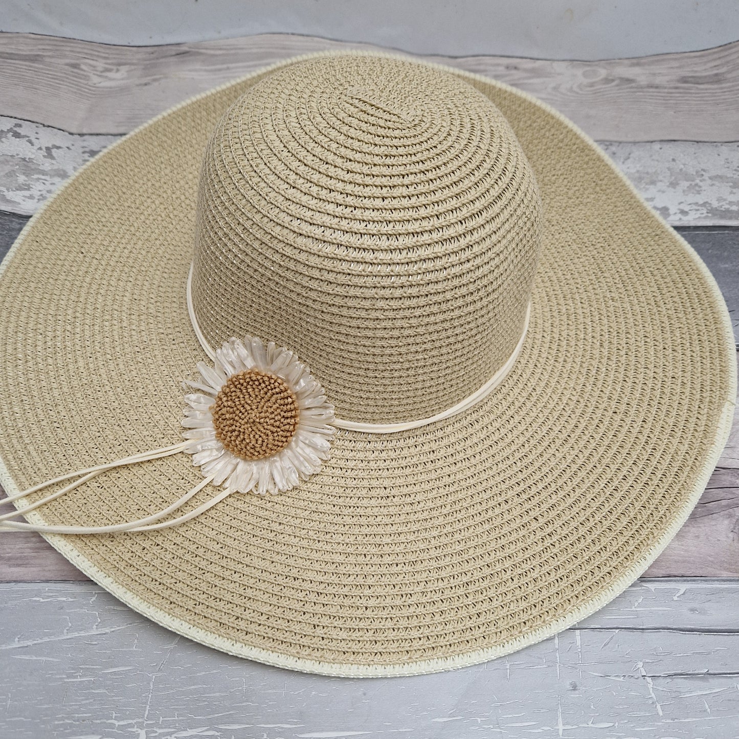 Wide brimmed hat decorated with a daisy flower.