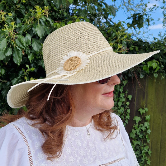 Wide brimmed hat decorated with a daisy flower.