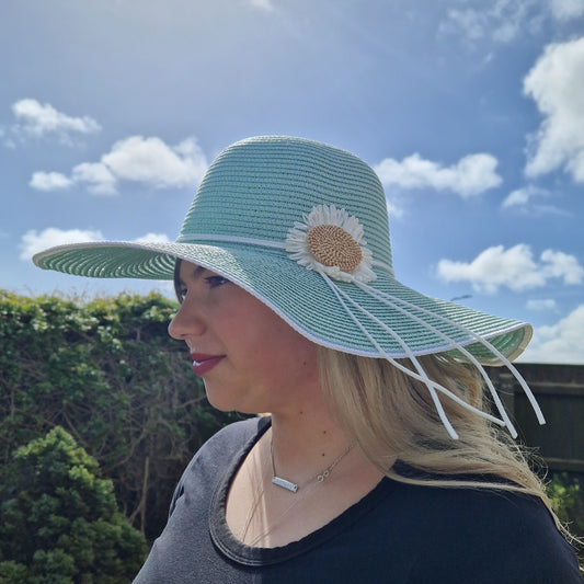 Wide brimmed mint green hat decorated with a daisy flower.