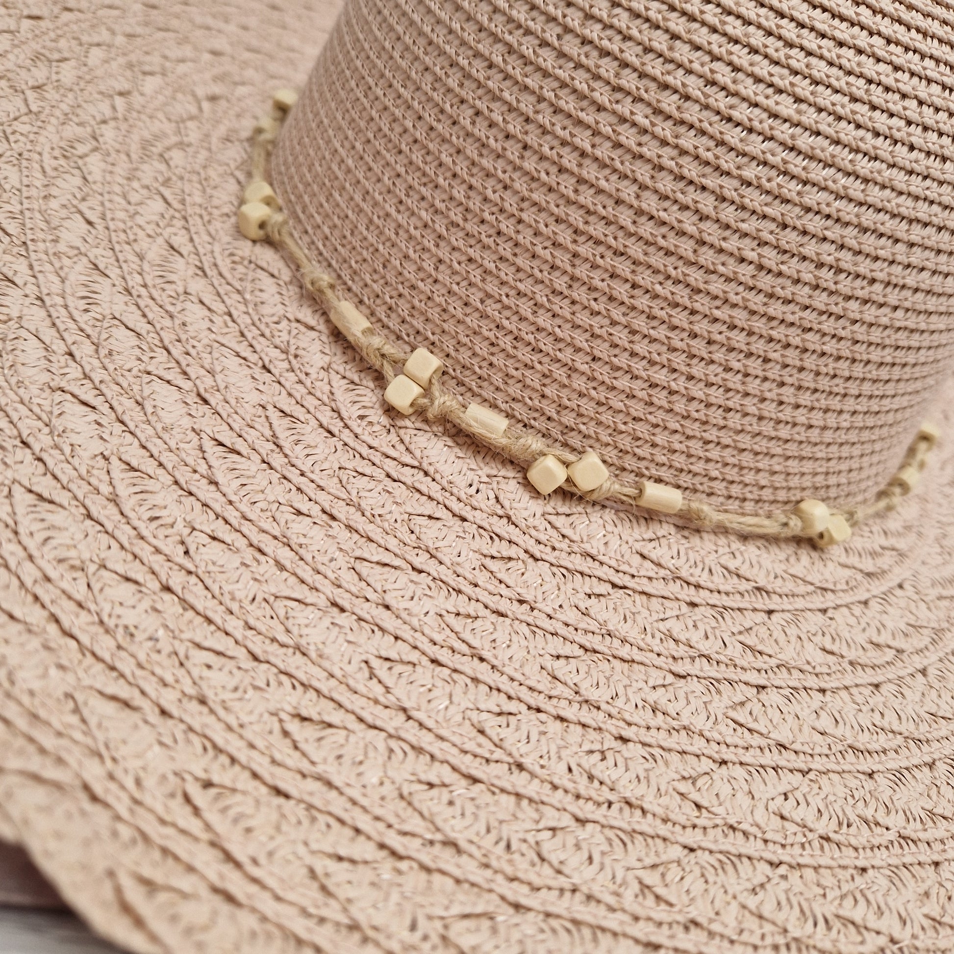 Pale pink wide brimmed hat with a beaded band.