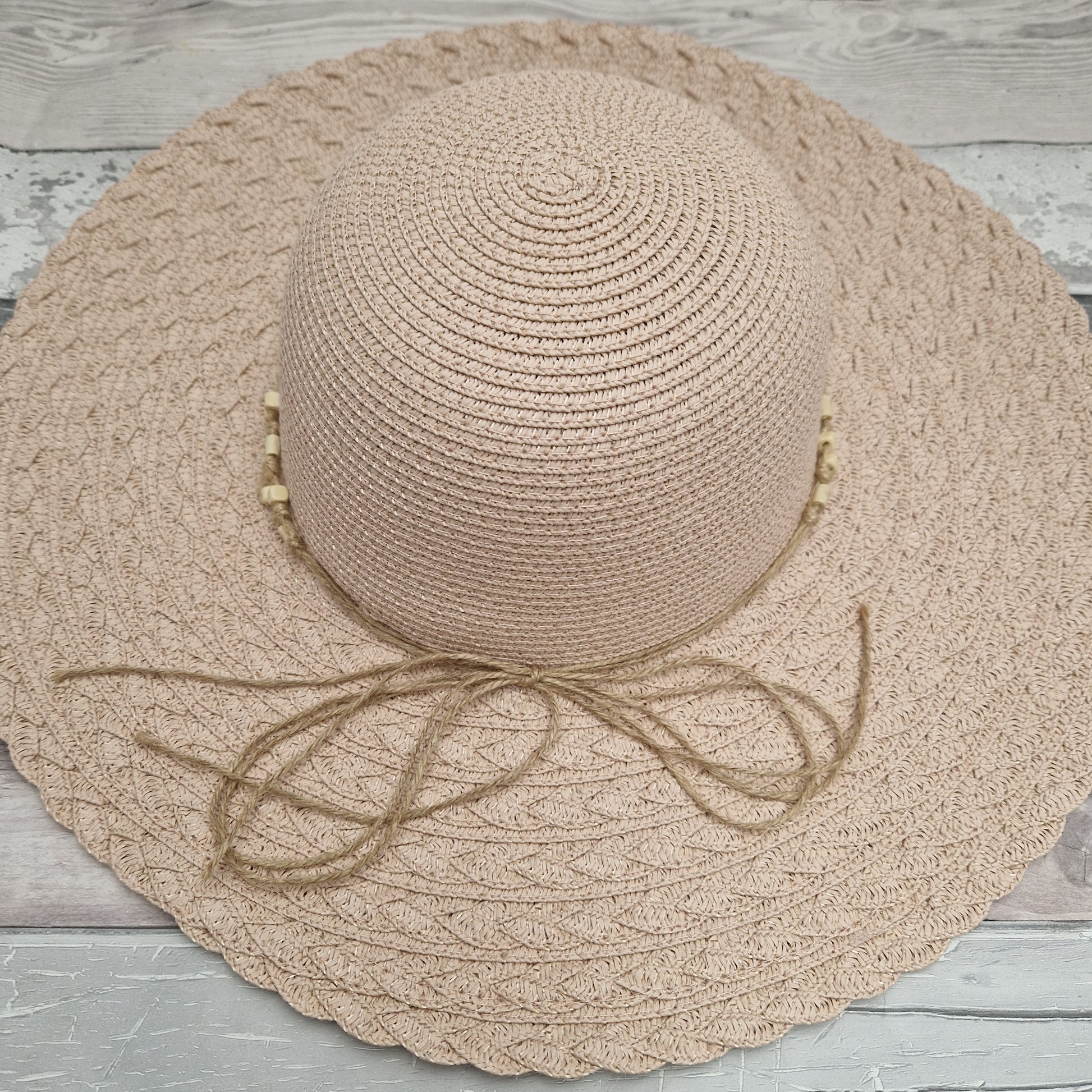 Pale pink wide brimmed hat with a beaded band.