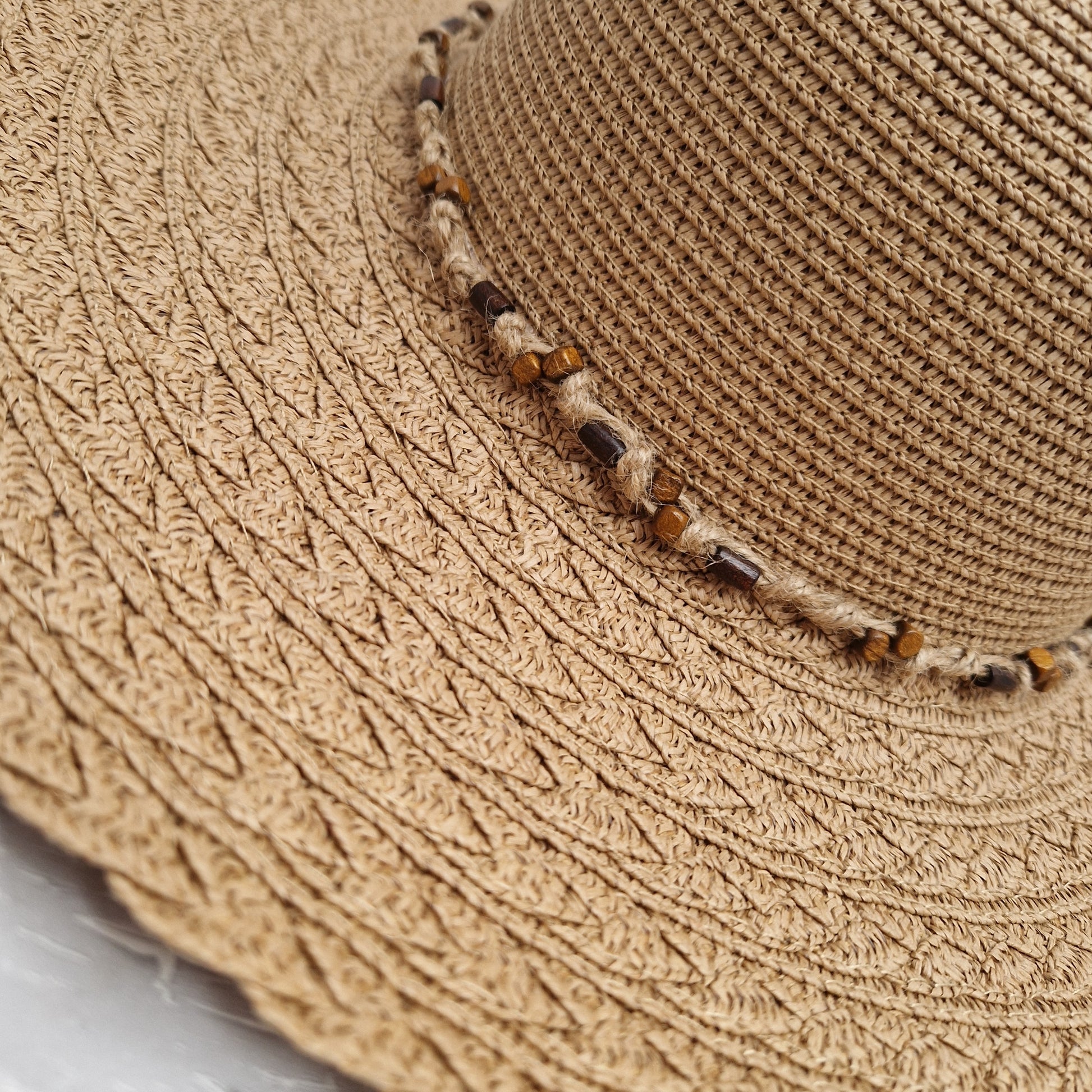 Lady wearing a natural coloured wide brimmed hat with a beaded band.
