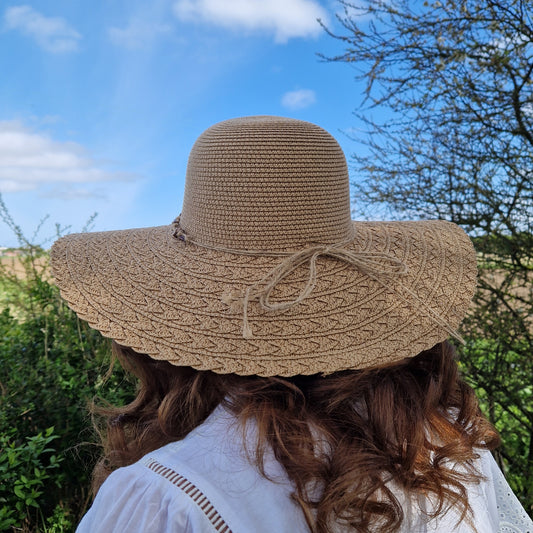 Lady wearing a natural coloured wide brimmed hat with a beaded band.