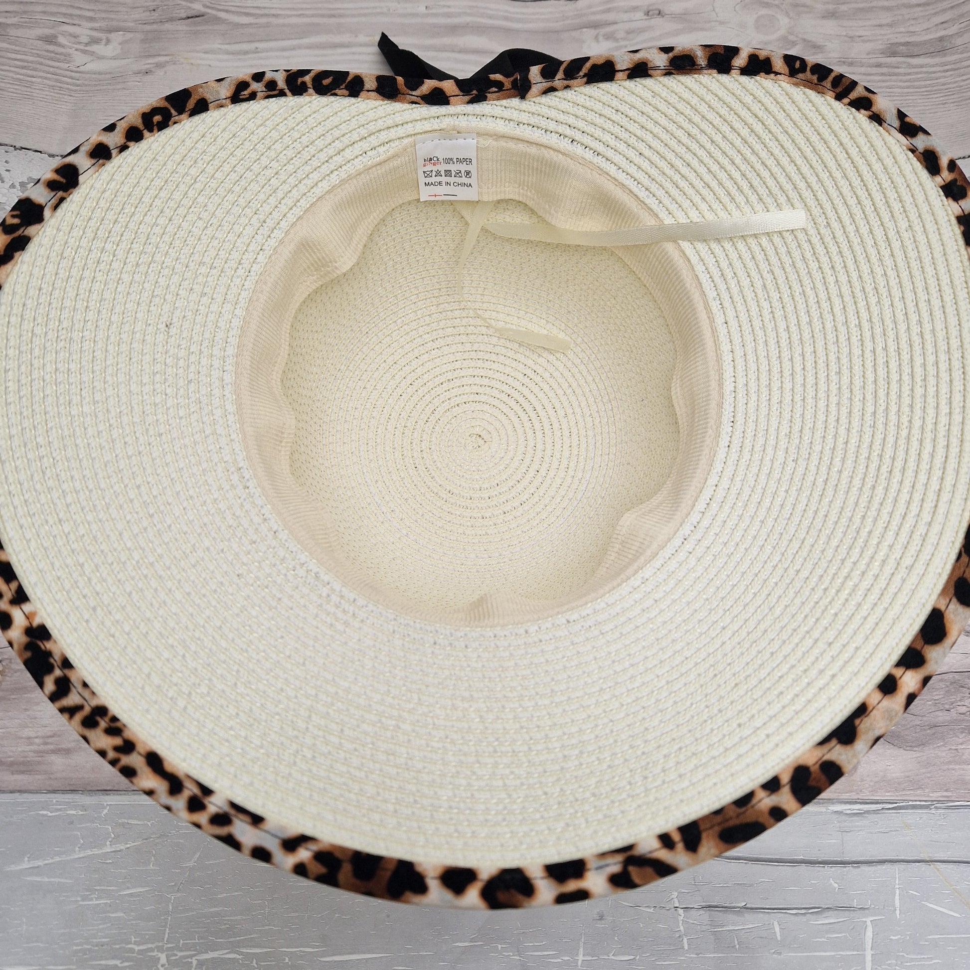 Cream open backed hat with an animal print trim and black bow.