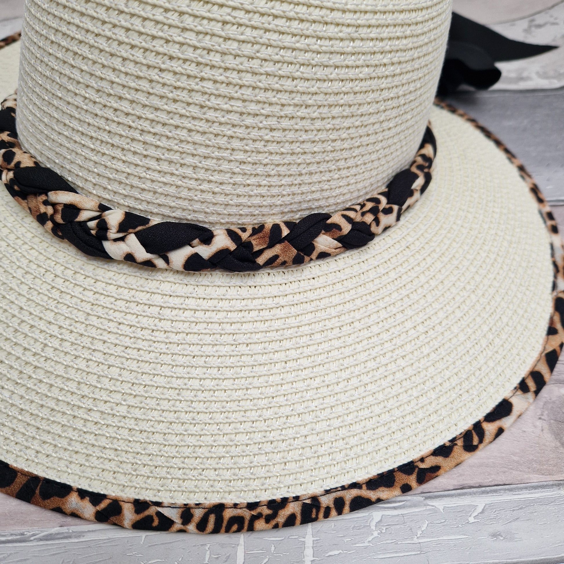 Cream open backed hat with an animal print trim and black bow.