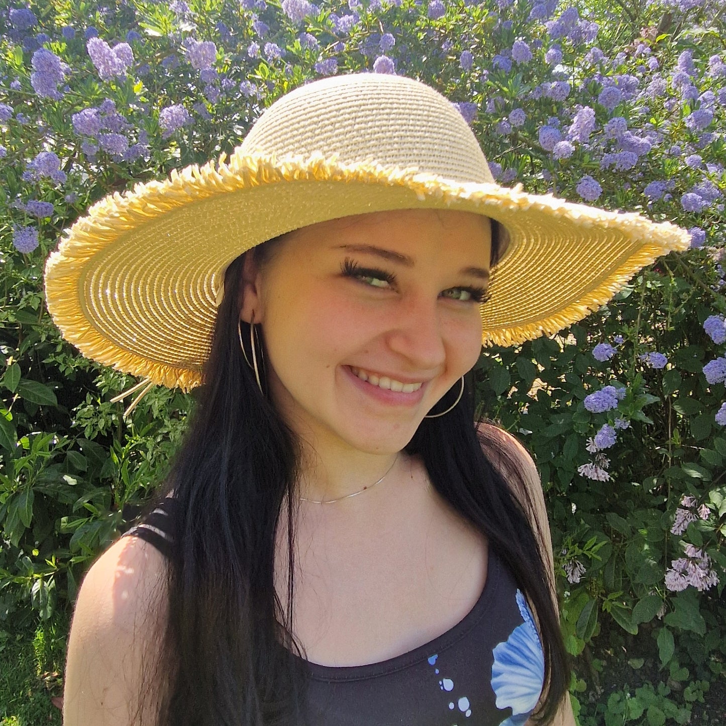 Young woman wearing a natural coloured wide brimmed hat with a frayed edging.